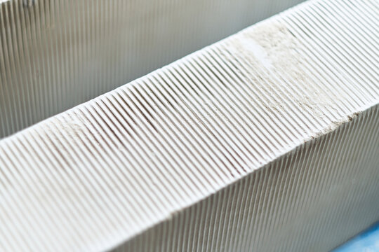 Close up of white aerated concrete blocks with ribbed texture for construction and building materials. Building regulations and quality control cement shape making.