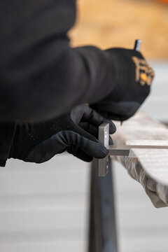 Main d'un artisan avec gants utilisant une &eacute;querre et un crayon pour marquer une pi&egrave;ce de bois avec pr&eacute;cision.