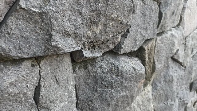 Close-up view of a rough stone wall texture with natural variations.