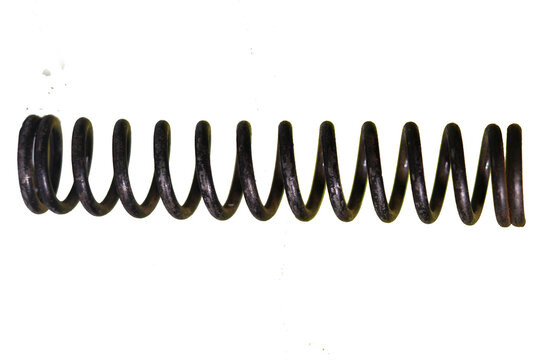 A tightly coiled metal spring is dramatically isolated against a solid black background high-quality professional