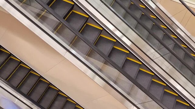 Modern escalators in commercial building interior featuring yellow safety lines and sleek design
