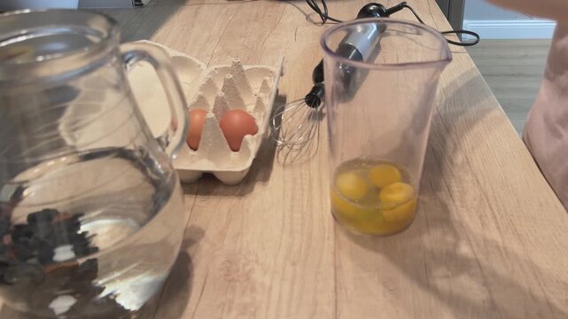 Breaking raw chicken eggs into cup for batter preparation Cooking ingredients process baking and breakfast food concept