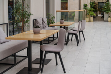 Fototapeta premium Wooden dining table and chairs in a minimalist cafe setting, bright morning light, modern interior.