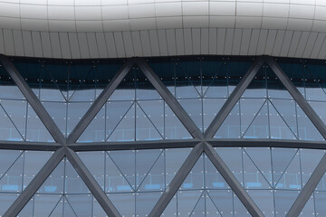 Fototapeta premium Modern glass facade with triangular structure and reflective windows. Architectural detail shows geometric pattern and clean design. Urban concept about structure, city environment