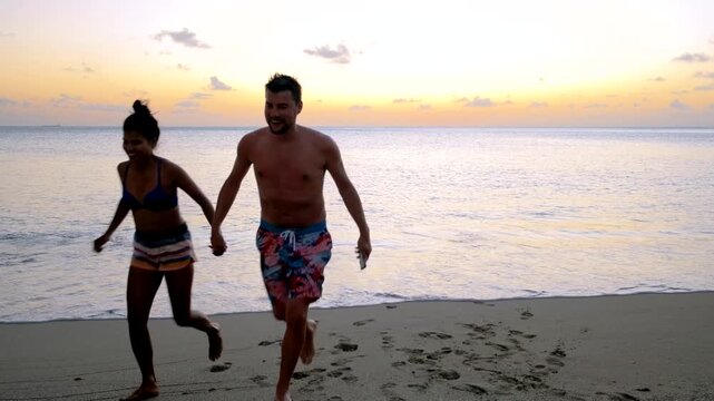 A couple enjoys a romantic evening walk along the beautiful sandy beach of St Lucia as the sun sets, creating a perfect golden glow over the tranquil waters.