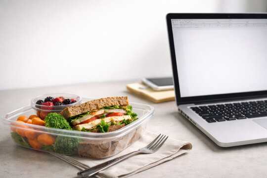 Workplace mental health lunch laptop sandwich Healthy workplace lunch beside laptop supporting mental health with sandwich vegetable fruit meal