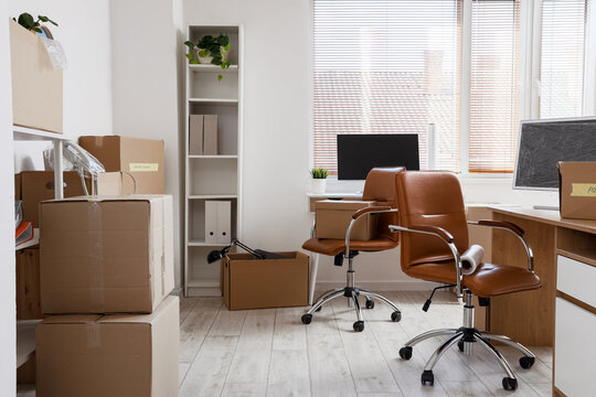 Desks with cardboard boxes in light office on moving day
