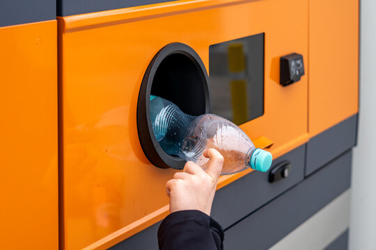Hand putting plastic PET bottle into a modern recycling vending machine, deposit return system and waste segregation, eco-friendly urban solutions, environmental protection and plastic recovery.