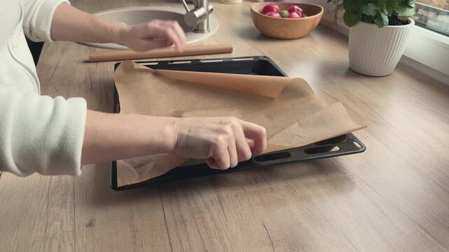 Parchment is unrolled directly onto baking tray and curls back up. Useful for baking tutorials kitchen tips food preparation and domestic routine videos. 