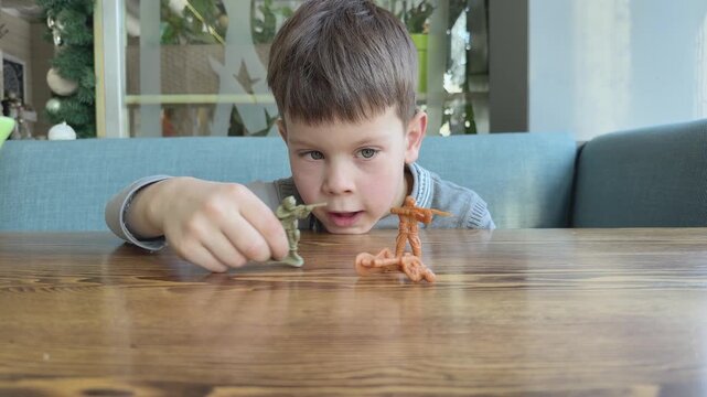 Wide view of boy playing with toy soldiers on table. Child imagination, roleplay and storytelling through game. Ideal for parenting, education and lifestyle content.