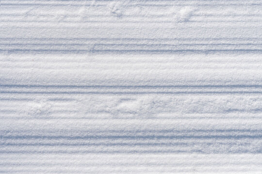 Groomed ski lane with grooves, wide horizontal corduroy texture and clean compact surface as background