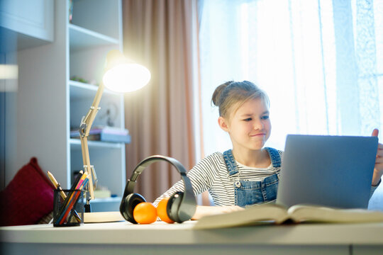 Student girl studying something using computer and headphones at home