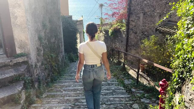 Rear View Woman Walking in Charming Streets of Lake Como, Italy, Scenic Travel Lifestyle with Beautiful Lake Views and European Architecture