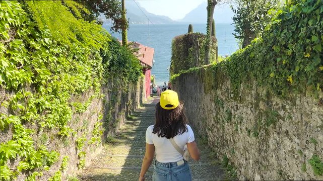 Rear View Woman Walking in Charming Streets of Lake Como, Italy, Scenic Travel Lifestyle with Beautiful Lake Views and European Architecture