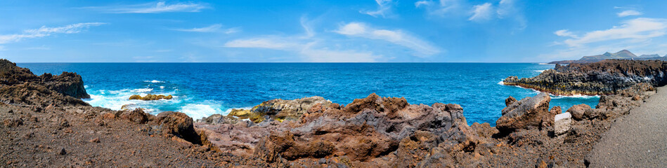 Fototapeta premium Panoramic view of Playa de Montana Bermeja with lava coast, Atlantic Ocean and blue summer sky on Lanzarote.