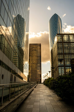 Sunset on a modern urban walkway with skyscraper architecture for business finance in Paris La Defense showing warm light and glass reflections