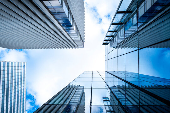 Upward glass perspective with symmetry in a skyscraper architecture for business finance in urban Paris La Defense under blue sky and clean lines