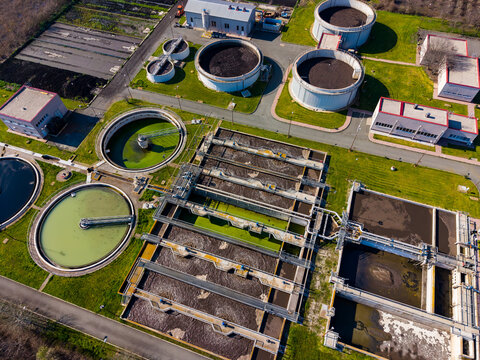 Workers manage a wastewater treatment plant in a suburban area during the day while equipment runs to clean water