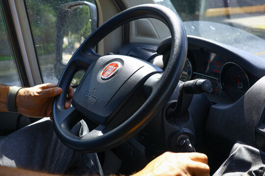 Driver&rsquo;s hands on a Fiat Ducato steering wheel in bright natural light, highlighting the interior design details, tactile controls and the everyday atmosphere of operating a compact modern vehicle