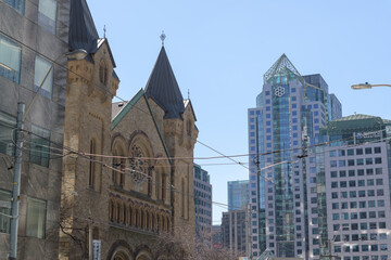 Naklejka premium a view of Metro Hall (55 John St), a municipal office complex and facade of St. Andrew's Presbyterian Church (73 Simcoe St), looking west on King St W, Toronto