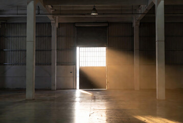Obraz premium A single light illuminates a doorway in an industrial warehouse, creating a dramatic and mysterious scene.