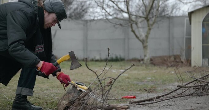 Men with kid cut branches in backyard and stockpile firewood in shed for winter. 4K 10-bit