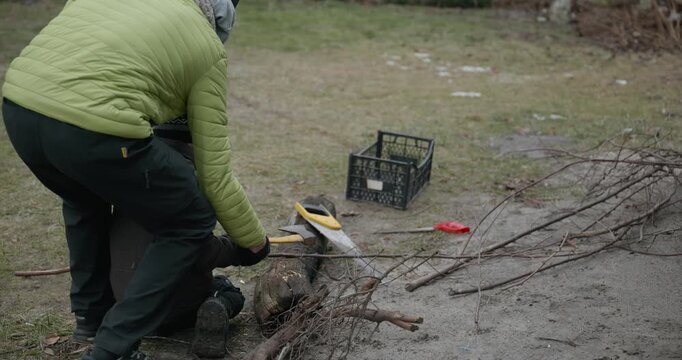 Men with kid cut branches in backyard and stockpile firewood in shed for winter. 4K 10-bit
