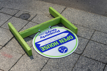 Obraz premium fallen Open House sign (Property Guys) on a granite pavement in downtown Toronto