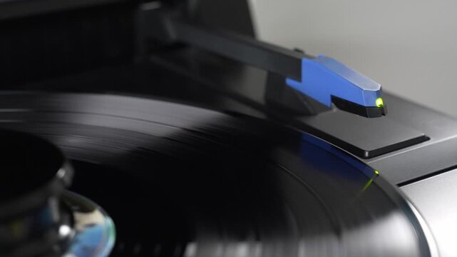 Stylus needle playing spinning vinyl record on turntable, analog music concept   