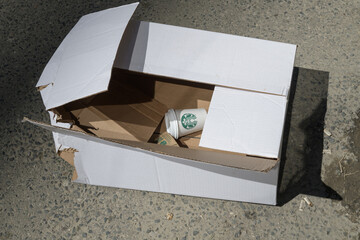 Naklejka premium discarded Starbucks coffee cup in an old white cardboard box on the street, Toronto