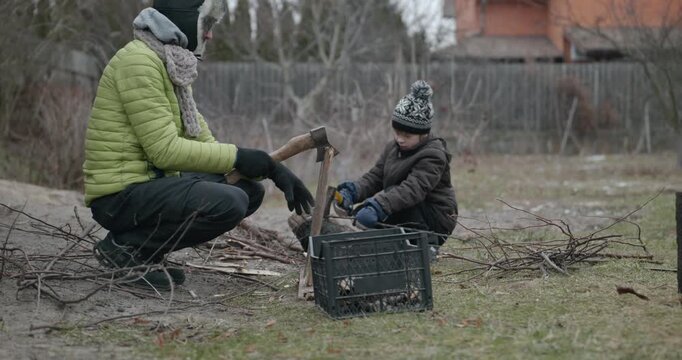 Men with kid cut branches in backyard and stockpile firewood in shed for winter. 4K 10-bit