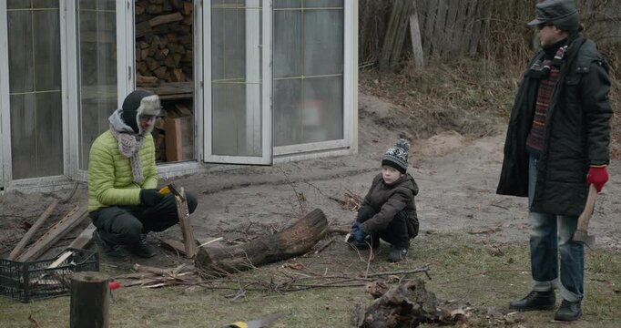Men with kid cut branches in backyard and stockpile firewood in shed for winter. 4K 10-bit