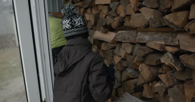 Men with kid cut branches in backyard and stockpile firewood in shed for winter. 4K 10-bit