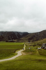 Winding trail through farmland toward misty mountains near Castle Hill Kura Tawhiti Conservation Area, Canterbury Region, New Zealand © apiwit