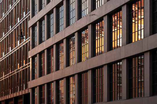 Urban warm atmosphere around modern office windows as symmetry pattern repeats across architecture building facade suggesting late work and city life