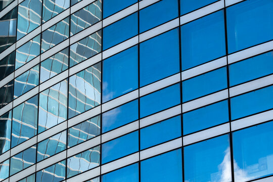 Abstract blue reflection pattern across glass windows grid on modern architecture building facade suggesting corporate growth and urban rhythm