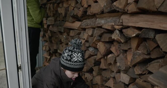 Men with kid cut branches in backyard and stockpile firewood in shed for winter. 4K 10-bit