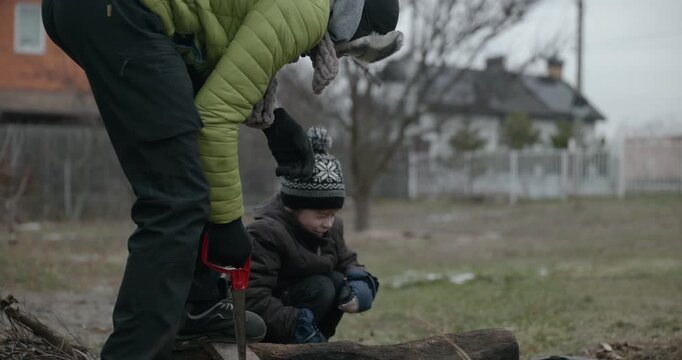 Men with kid cut branches in backyard and stockpile firewood in shed for winter. 4K 10-bit