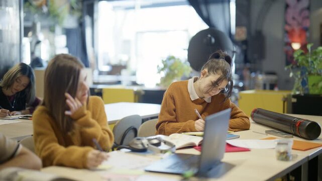 Young students diligently write and concentrate on their studies in a modern classroom. They are focused on academic work, fostering an active learning atmosphere.