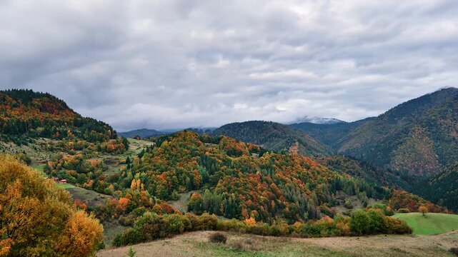Autumn mountain landscape with colorful forest under cloudy sky timelapse