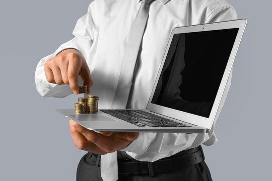 Businessman with laptop and money on grey background, closeup
