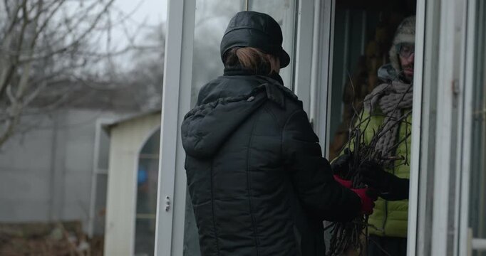 Men with kid cut branches in backyard and stockpile firewood in shed for winter. 4K 10-bit