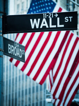 Close-up of Wall Street and Broad street street signs and American flags in front of the New York Stock Exchange, Manhattan, New York, USA