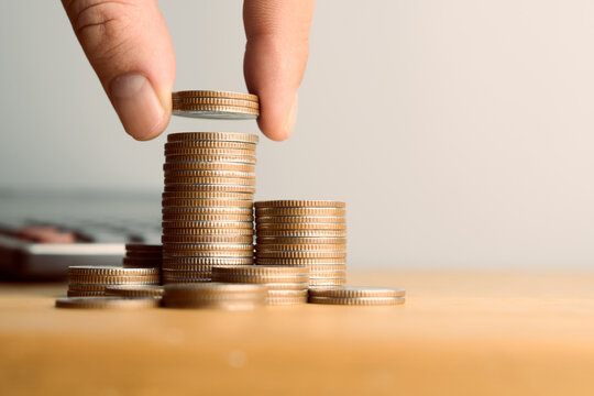 Close up of hand putting coin on stack of coins like a rising bar graph with copy space for financial growth, investment and saving concept