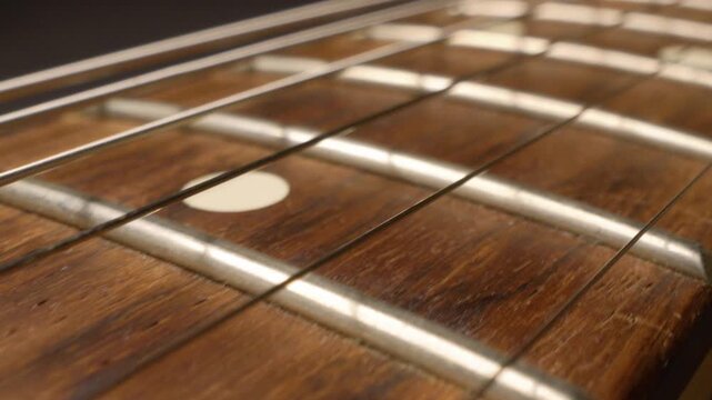 Camera movement along electric guitar fretboard, close-up of frets and strings