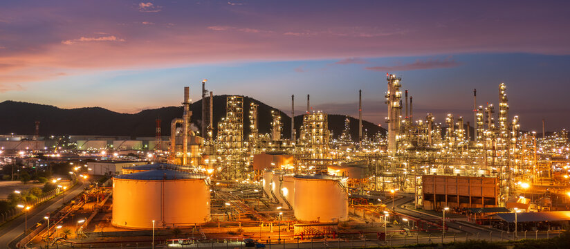 Aerial view of oil refinery and storage tanks at dusk and night, showcasing energy industry infrastructure, petroleum processing, and industrial landscape.