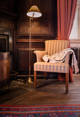 Fototapeta premium Elegant Ladies Coat Draped Ove The Arm Of A Chair In A Period Wooden Panelled Drawing Room
