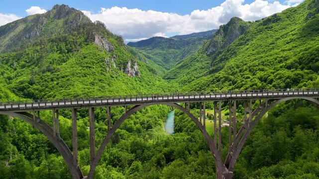 Aerial drone view of the Djurdjevica Tara arch bridge over the Tara River canyon, Montenegro. People enjoy the view. 