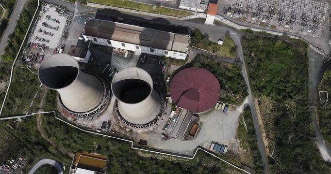 Larderello, Italy - 15 April 2026: Aerial view of Enel Green Power - Centrale Geotermica di Larderello with its iconic cooling towers and electrical substation surrounded by green hills.