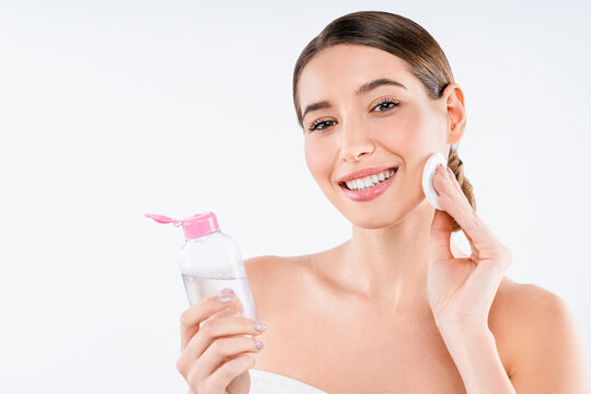 Young beautiful woman removing makeup with cotton pad and micellar water isolated on white background, facial cleansing, skincare treatment, cosmetic routine and natural beauty concept